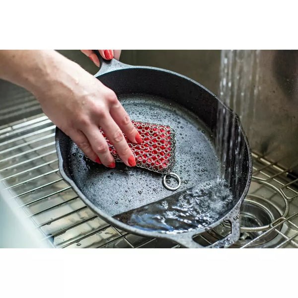 Lodge Chainmail Scrubbing Pad in red, in use.