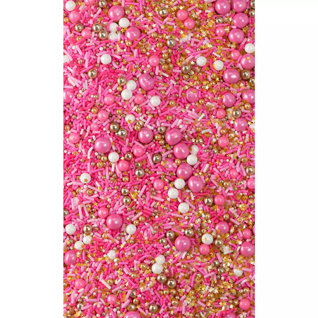 Close up of Flamingo sprinkles, bright and light pink strands, white strands, heaps of edible gold dragées, shimmery pink beads, sixlets, candy pearls, confetti sprinkles, edible gold, and nonpareils.